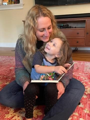 Young child reading a book with parent